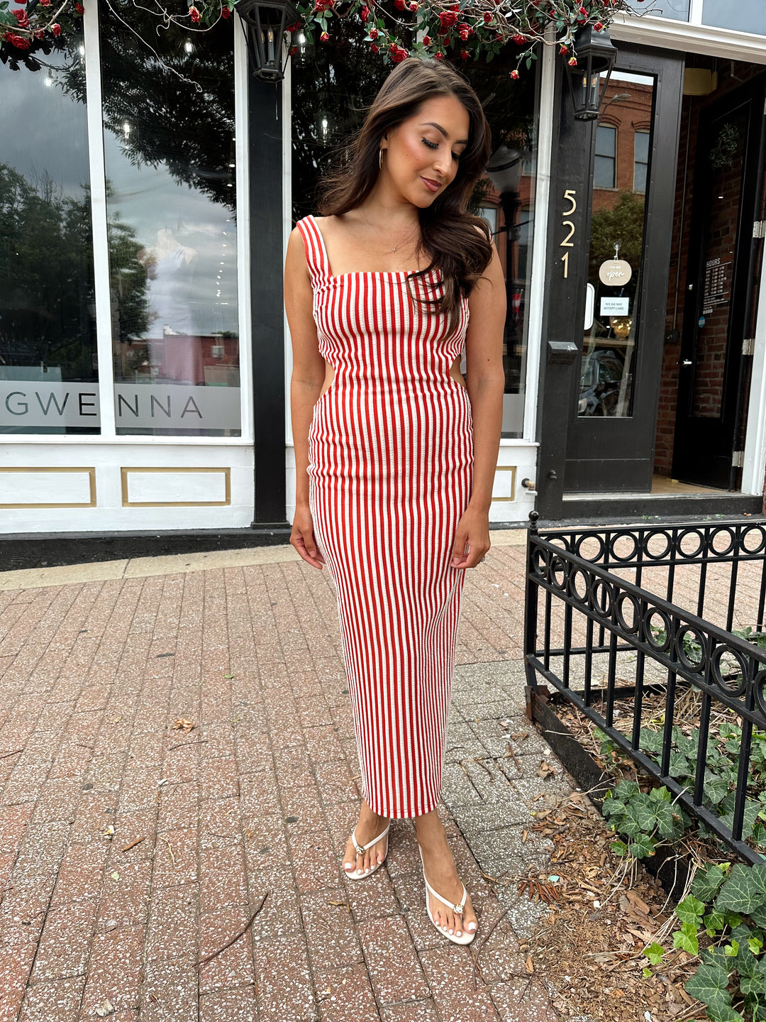 Woman wearing red and white striped textured midi dress with an open back. 