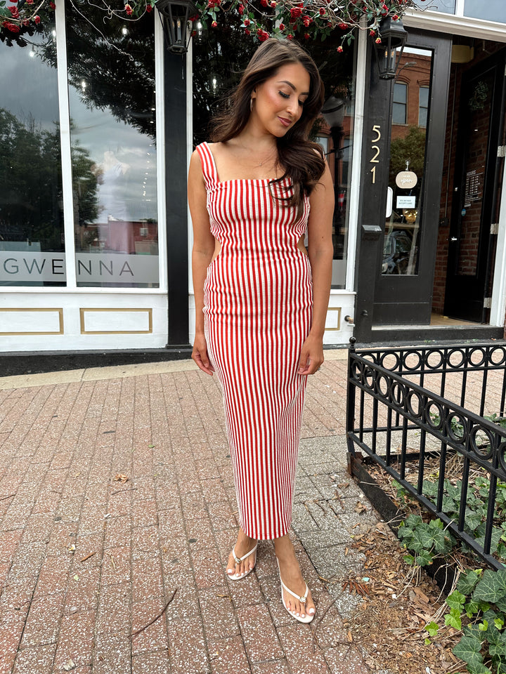 Woman wearing red and white striped textured midi dress with an open back. 