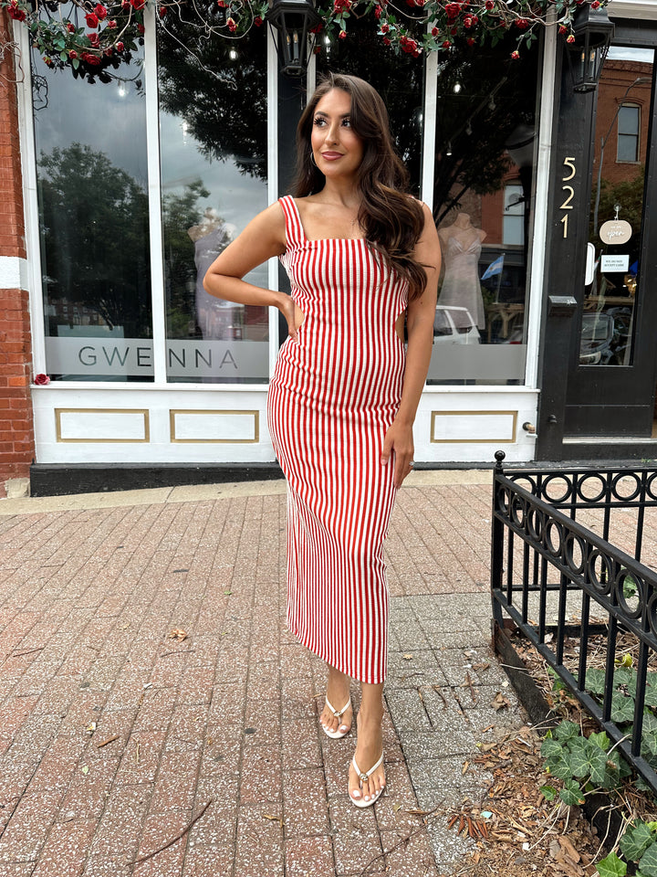 Woman wearing red and white striped textured midi dress with an open back. 