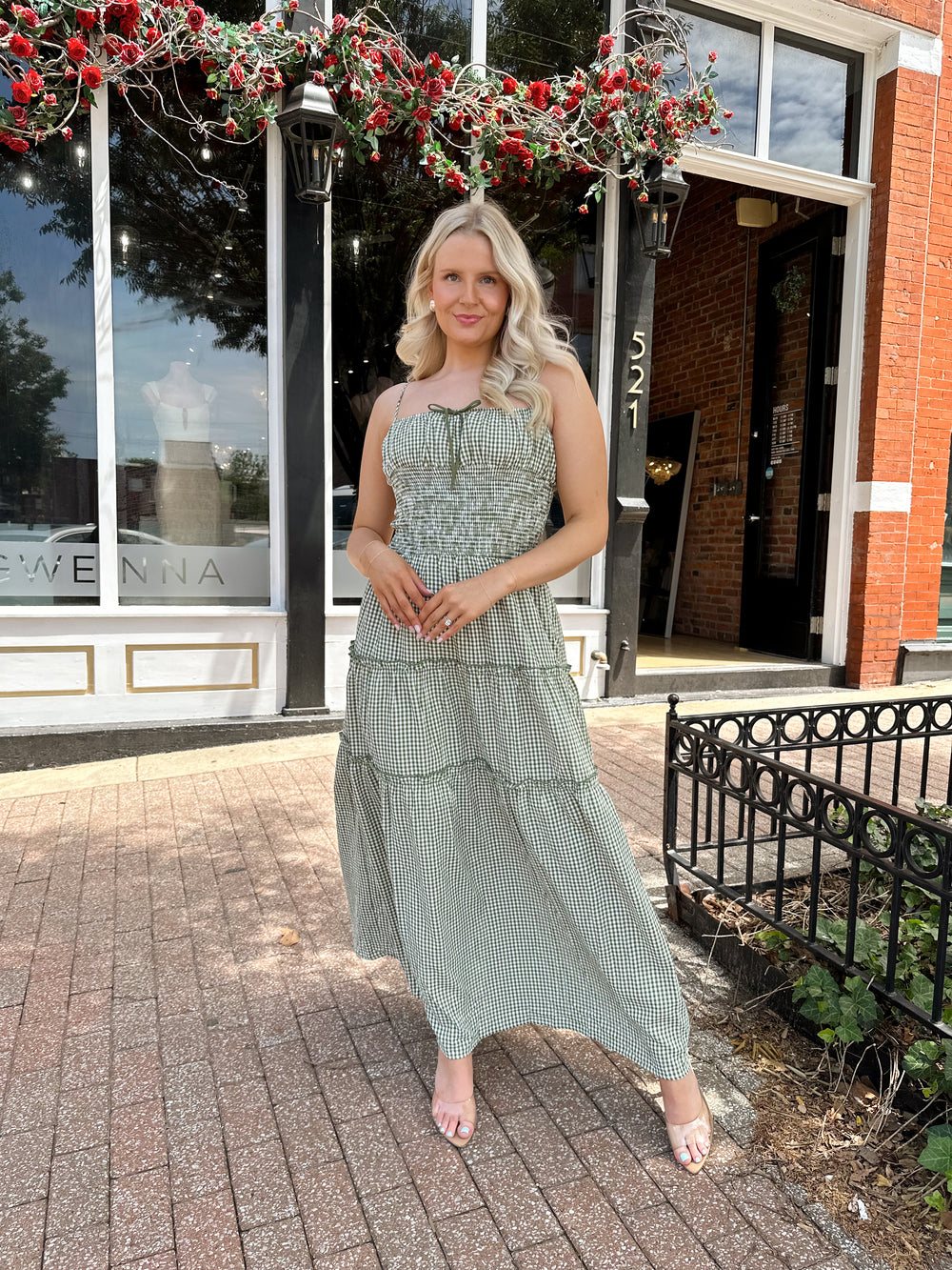 Woman wearing green gingham maxi dress with smocked midsection and adjustable straps.