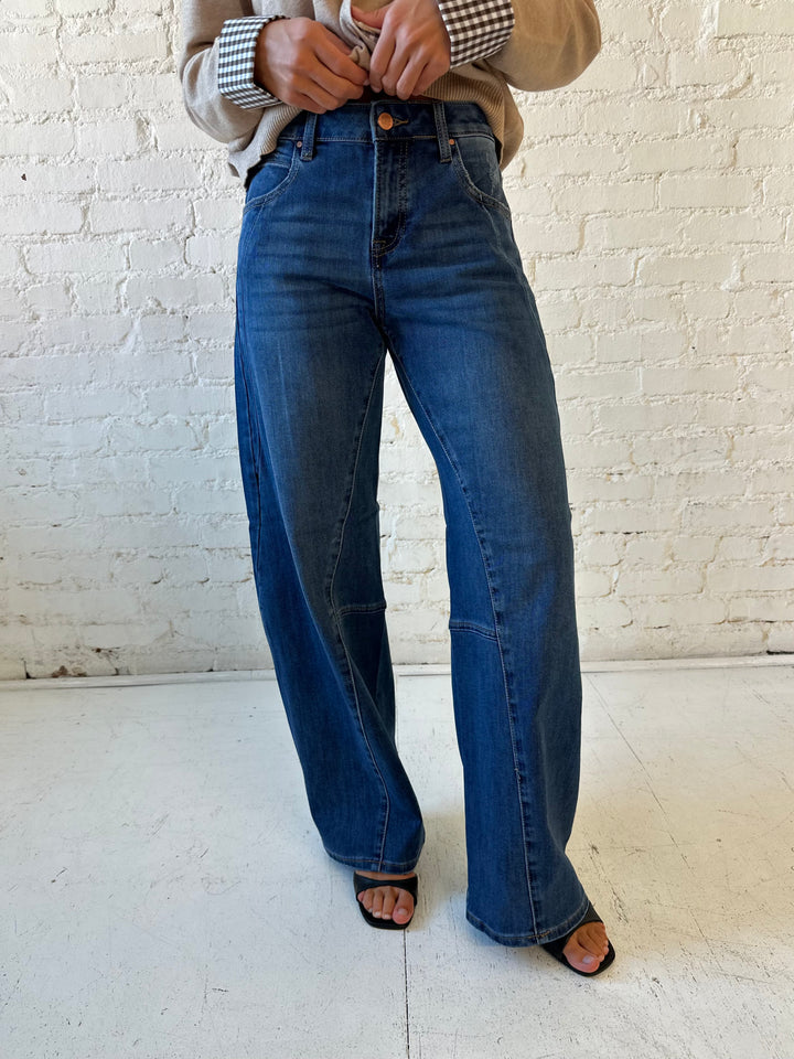 Woman wearing dark wash, slouchy barrel jean with sweater top. 