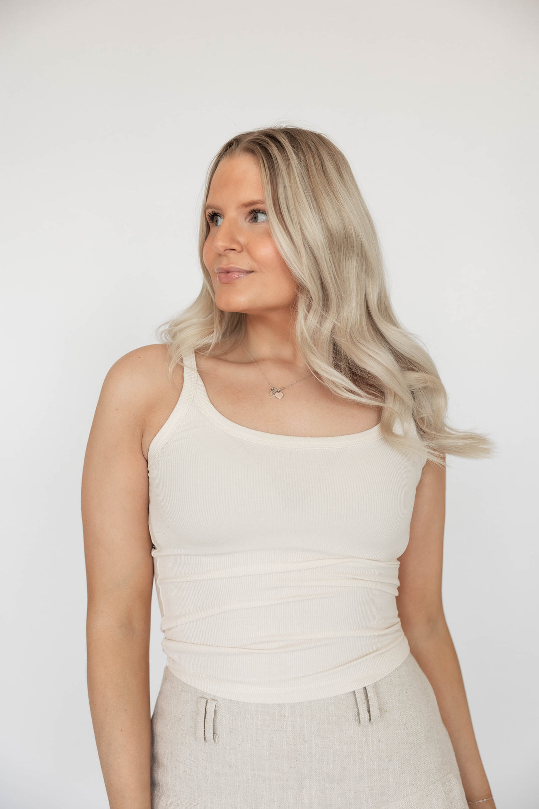 Woman wearing off white ribbed tank top.