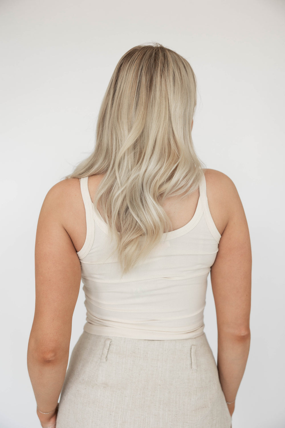 Woman wearing off white ribbed tank top.