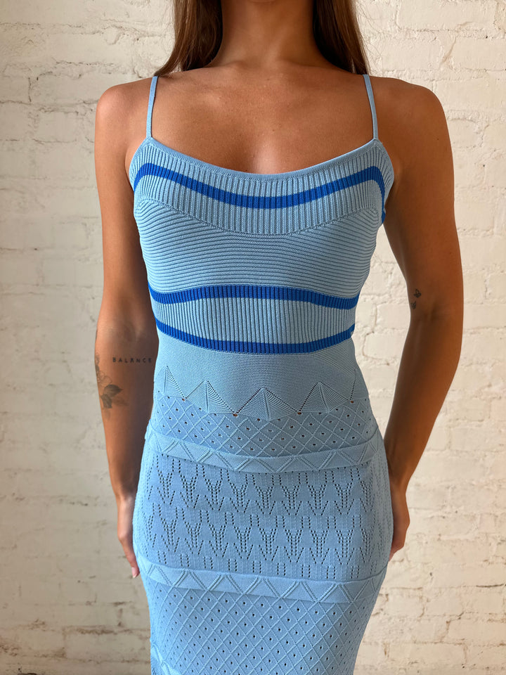 Woman wearing blue knit maxi dress with contrast blue lining, and side slit.