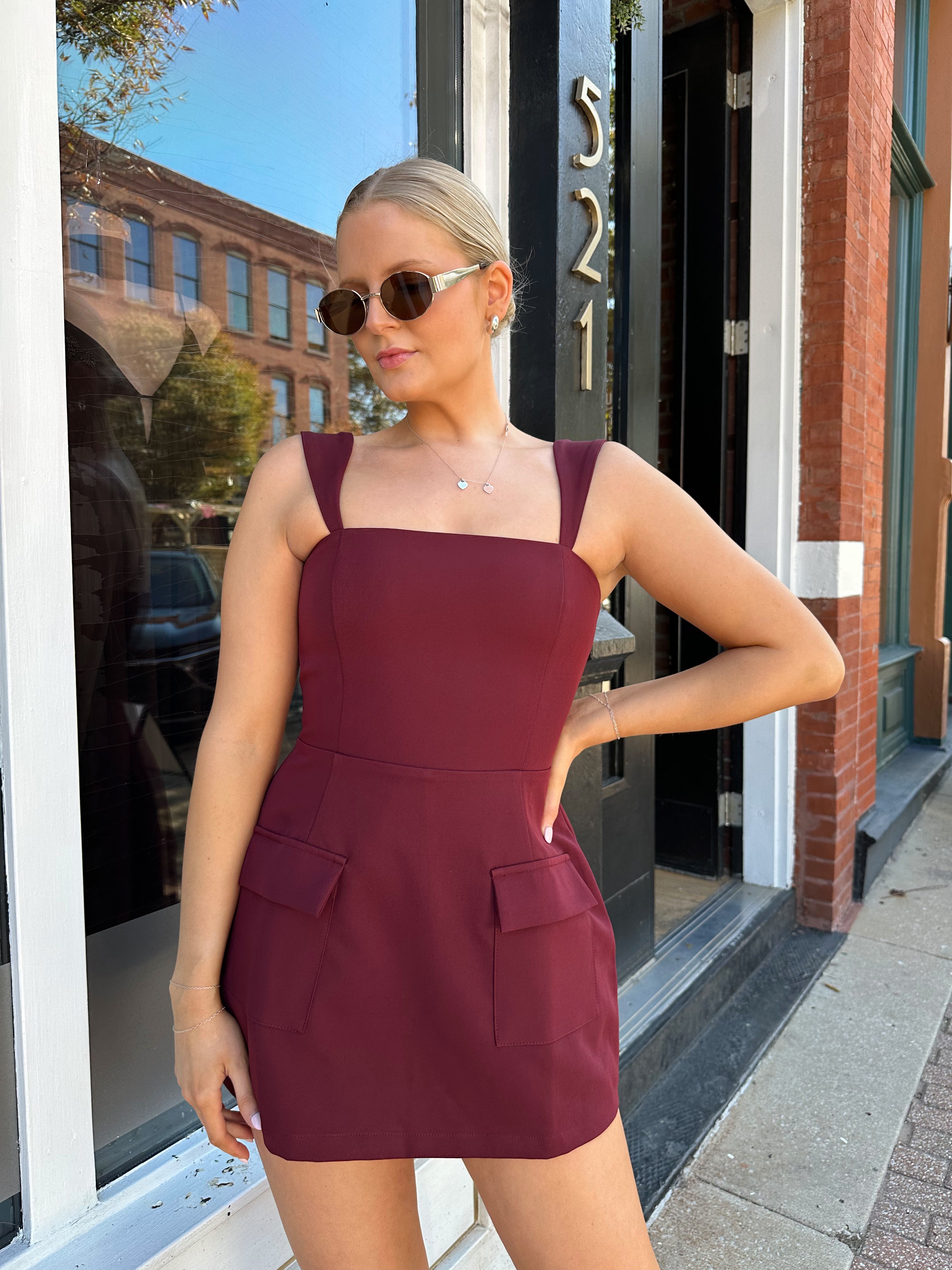 Woman wearing rose tailored mini dress with square neckline and front pockets.