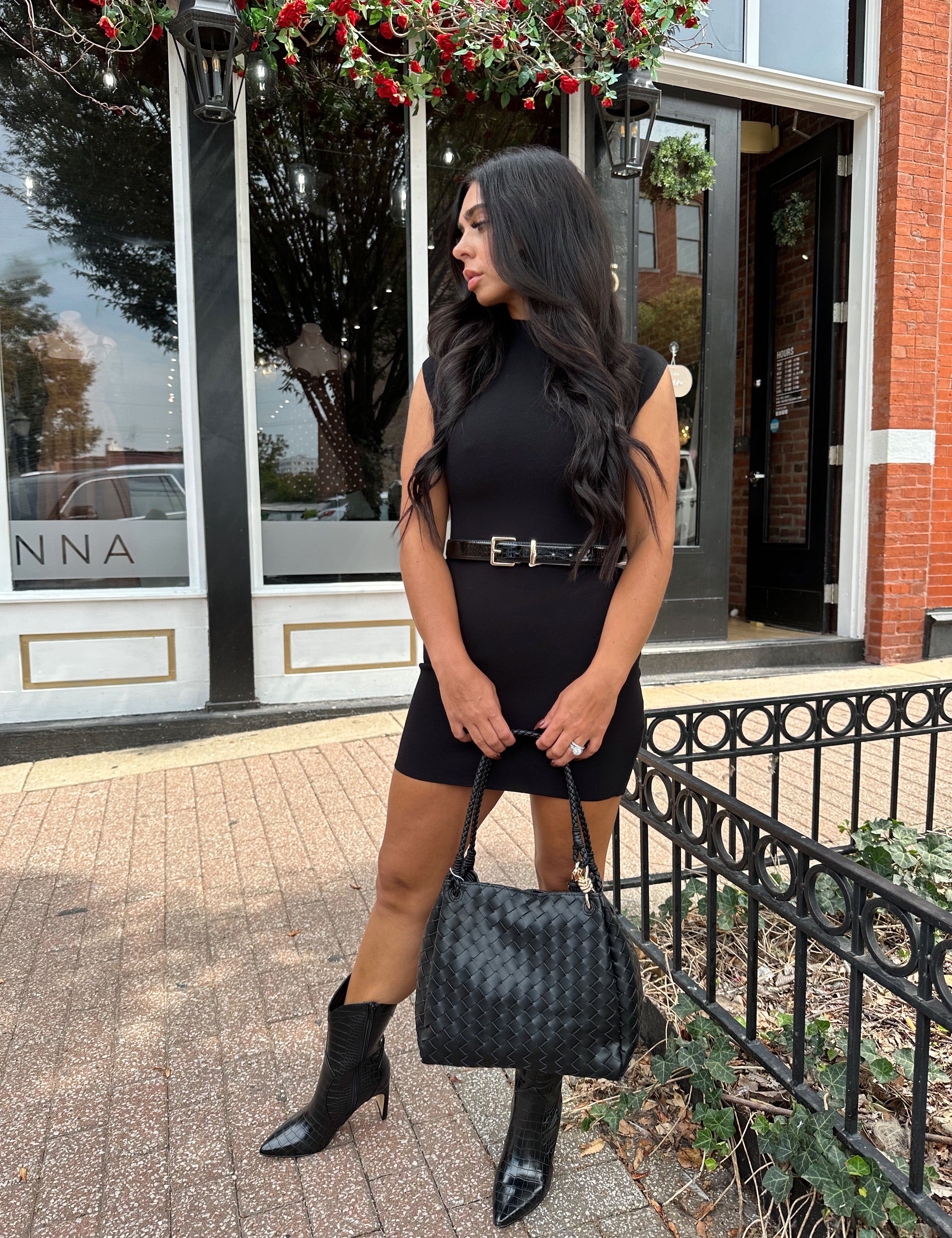 Woman wearing a black ribbed mock neck mini dress with belt.
