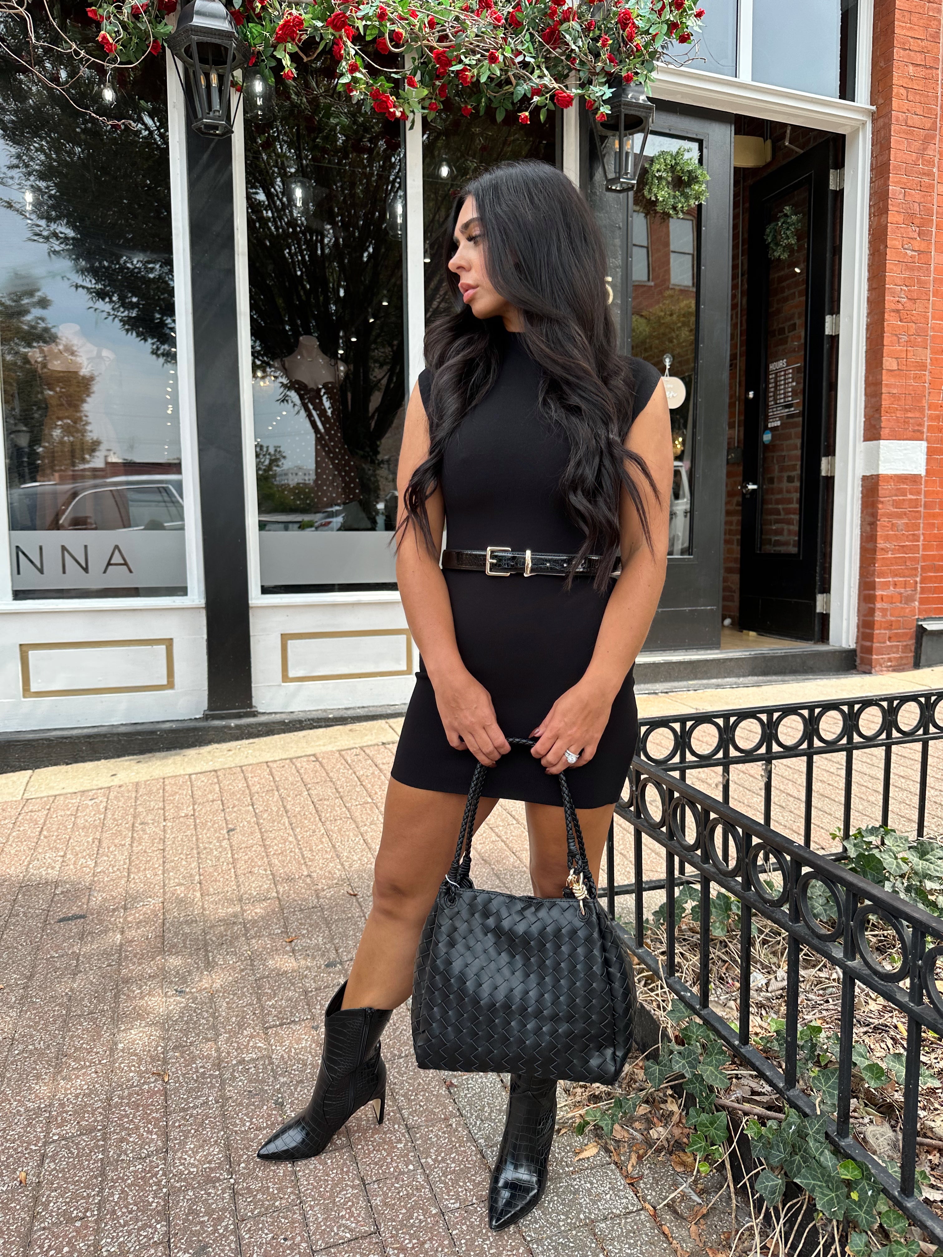 Woman wearing a black ribbed mock neck mini dress with belt.
