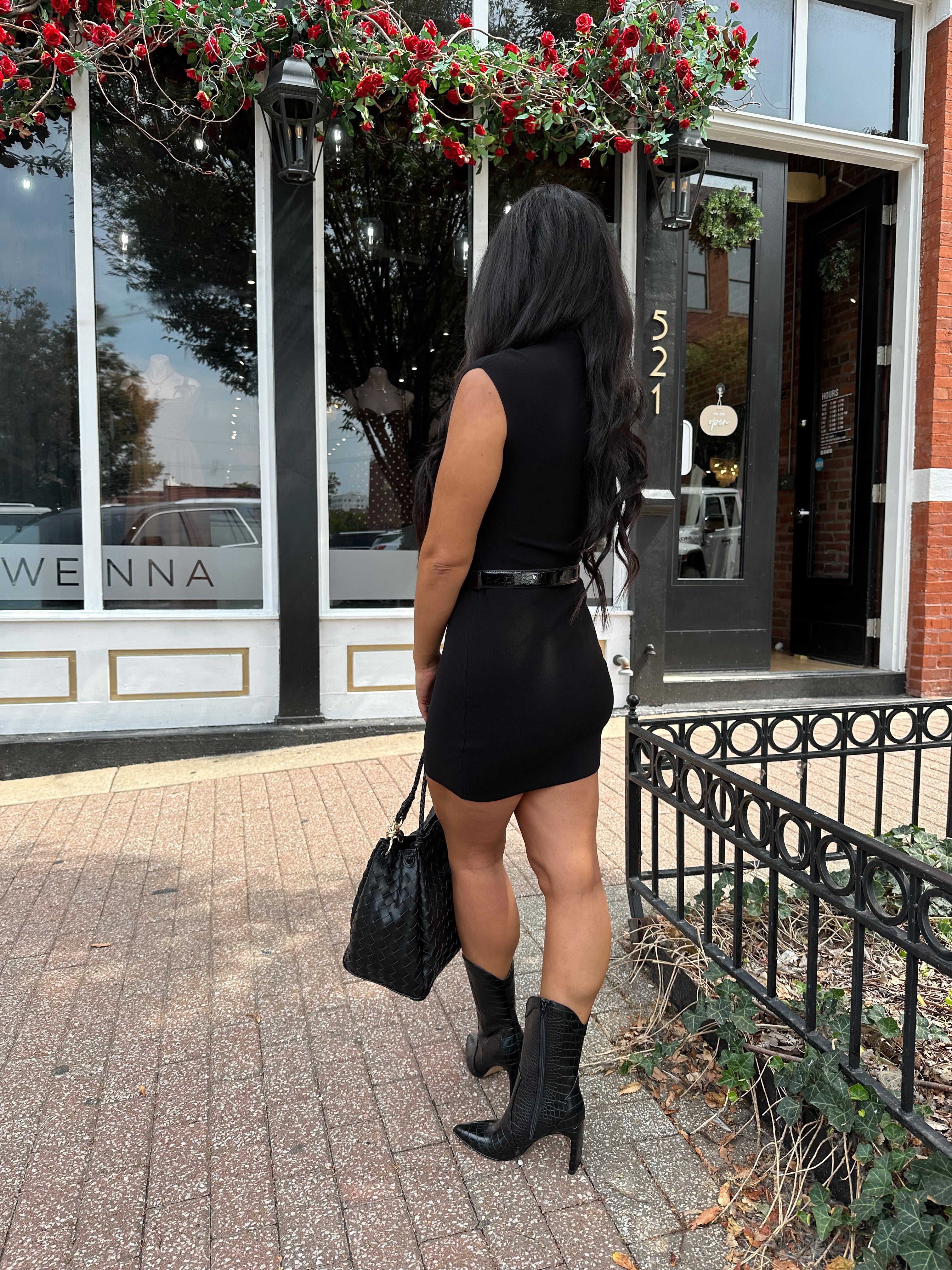 Woman wearing a black ribbed mock neck mini dress with belt.