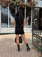 Woman wearing a black ribbed mock neck mini dress with belt.