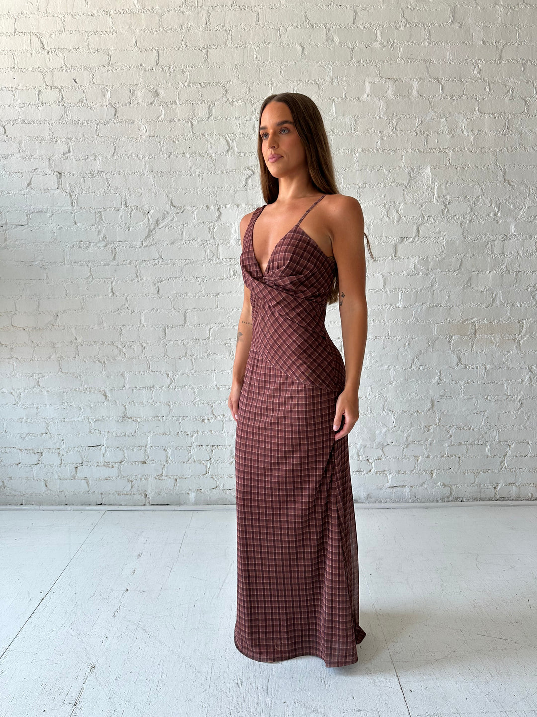 Woman wearing brown plaid asymmetrical maxi dress.