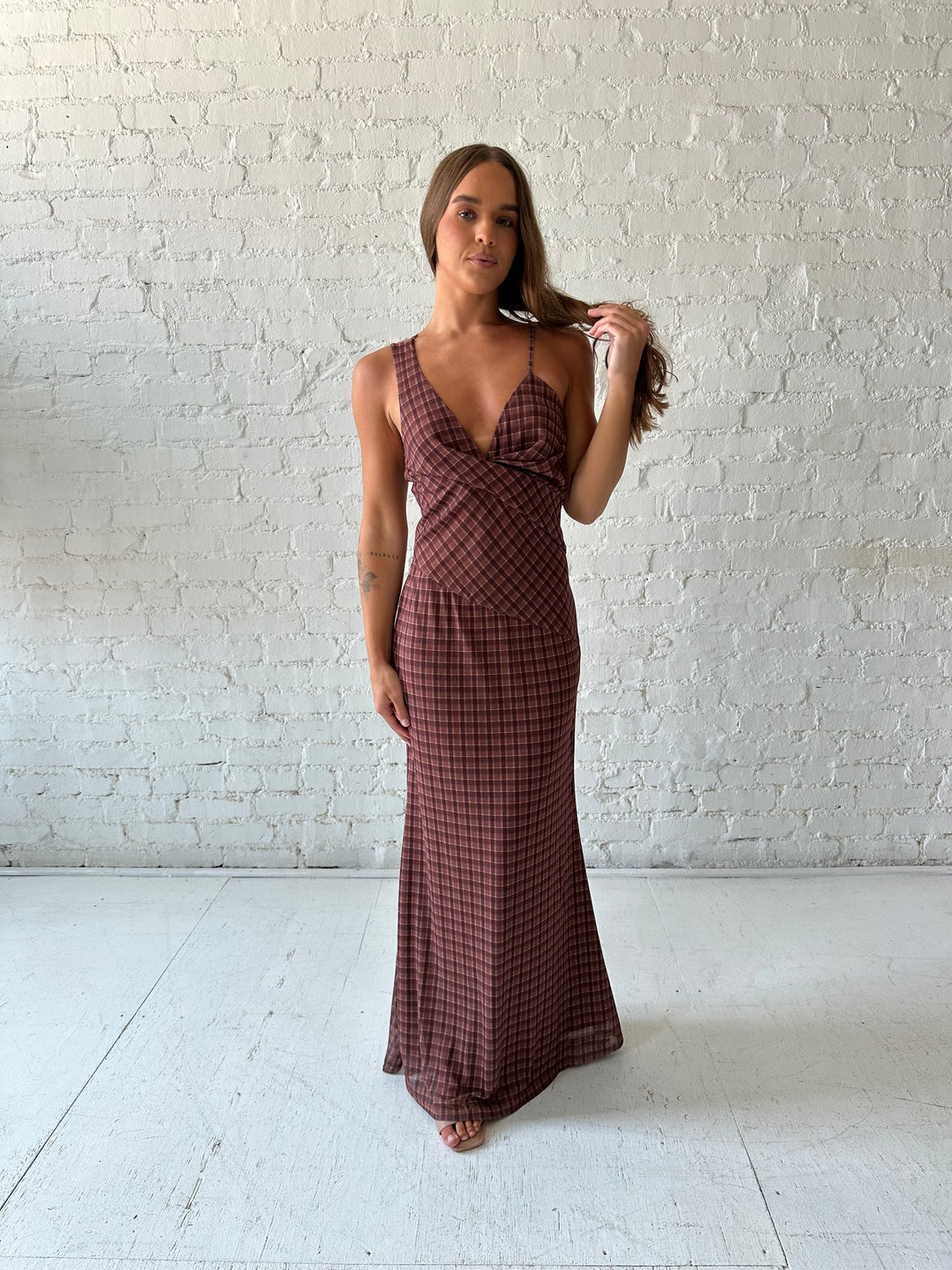 Woman wearing brown plaid asymmetrical maxi dress.