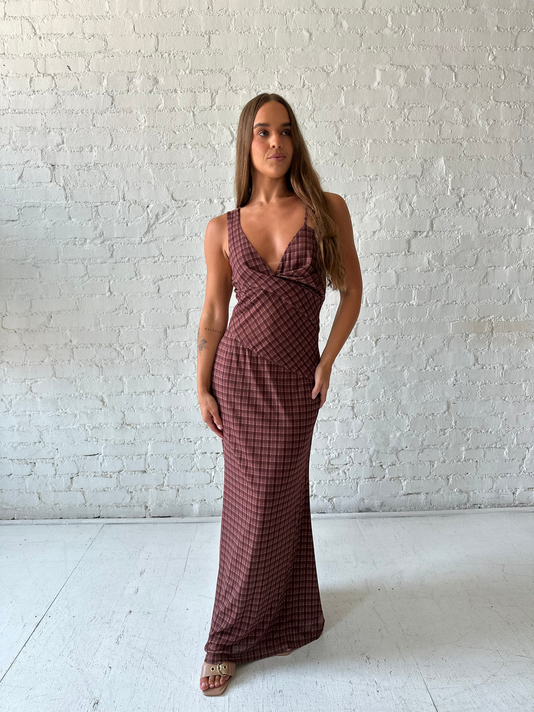 Woman wearing brown plaid asymmetrical maxi dress.
