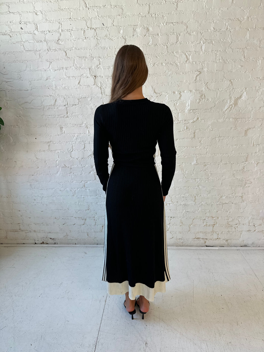 Woman wearing black long sleeve maxi dress with white contrast lining and belted midsection. 