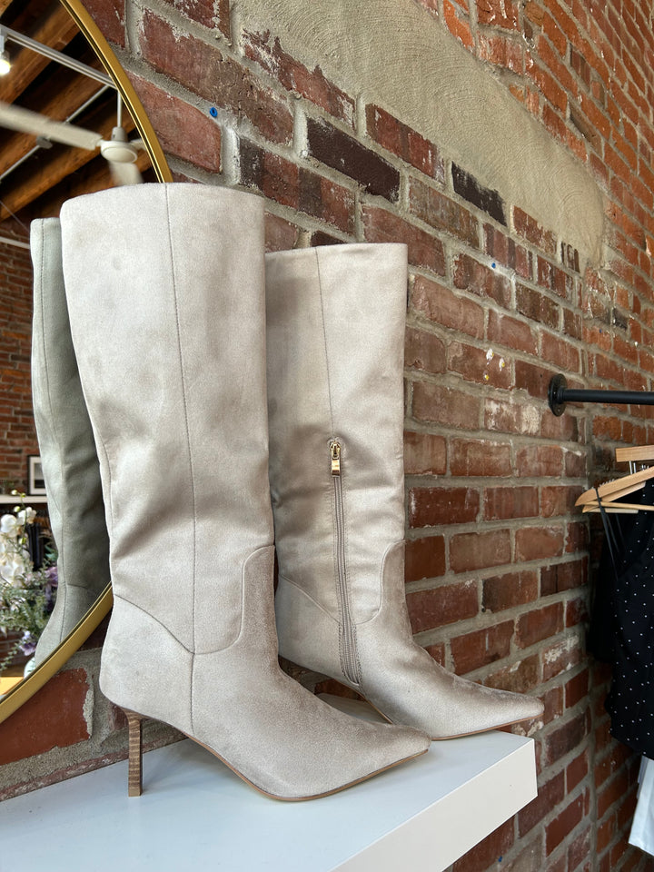 Oat colored suede tall knee boot with inner zip closure and stiletto heel.