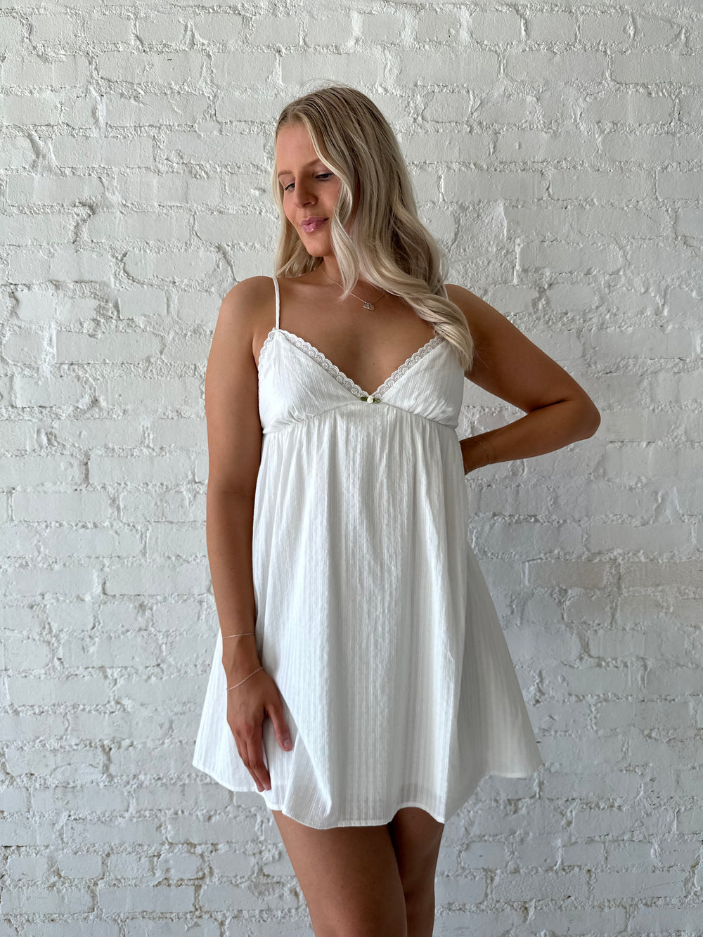 Woman wearing white mini dress with eyelet detailing. 