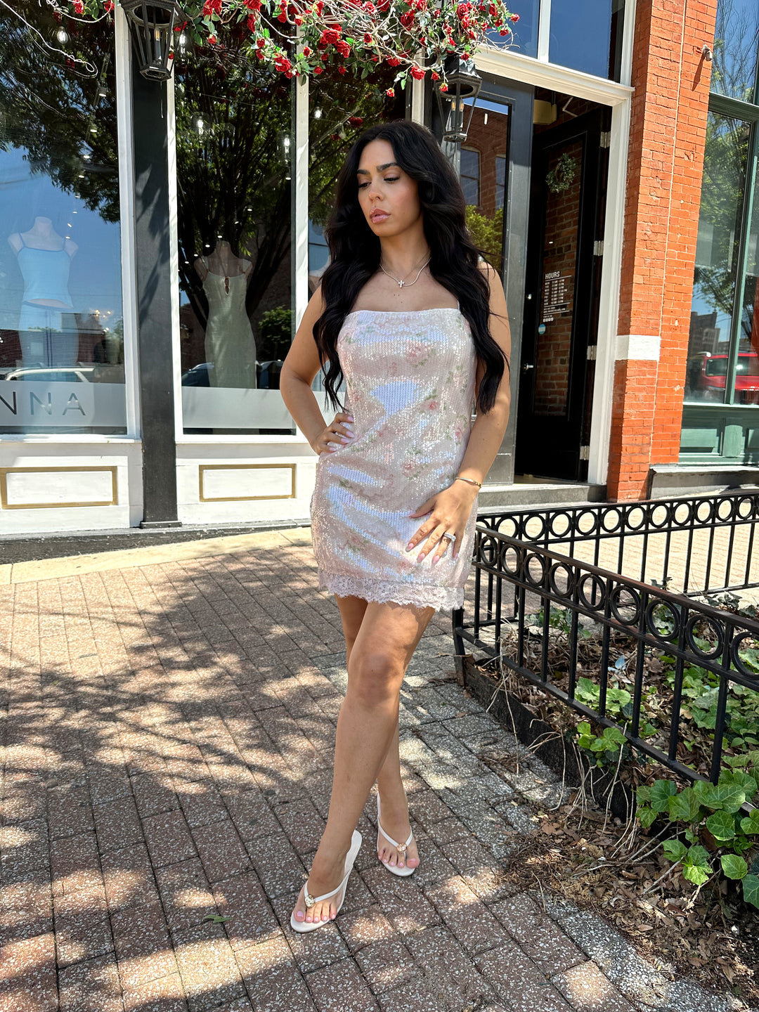 Woman wearing wearing blush pink sequin mini dress with rose pattern, and lace trim.