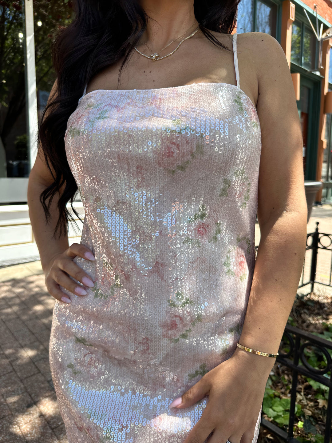 Woman wearing wearing blush pink sequin mini dress with rose pattern, and lace trim.