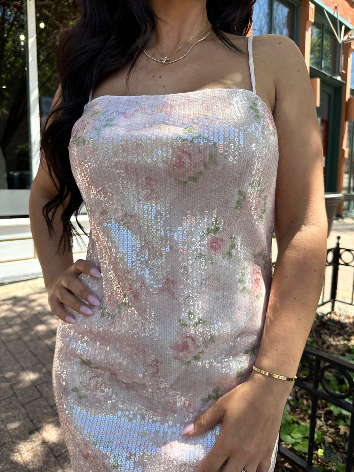 Woman wearing wearing blush pink sequin mini dress with rose pattern, and lace trim.