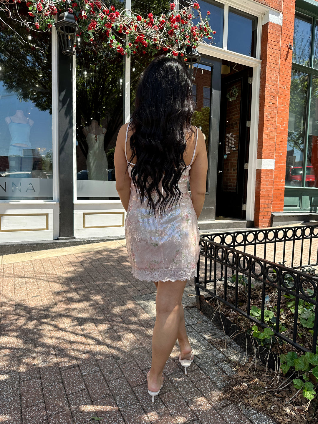 Woman wearing wearing blush pink sequin mini dress with rose pattern, and lace trim.