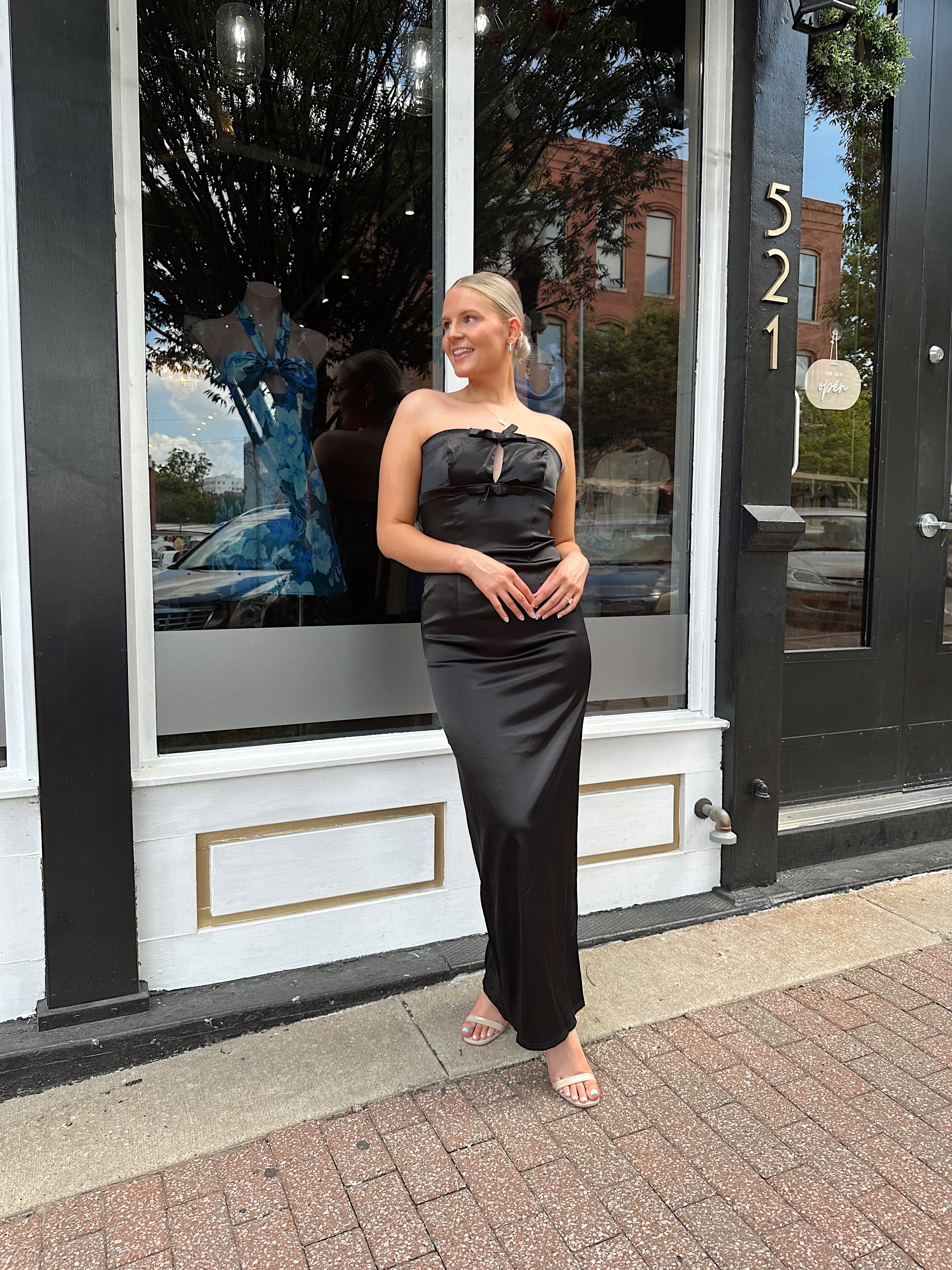 Black satin strapless midi dress with bow detail.