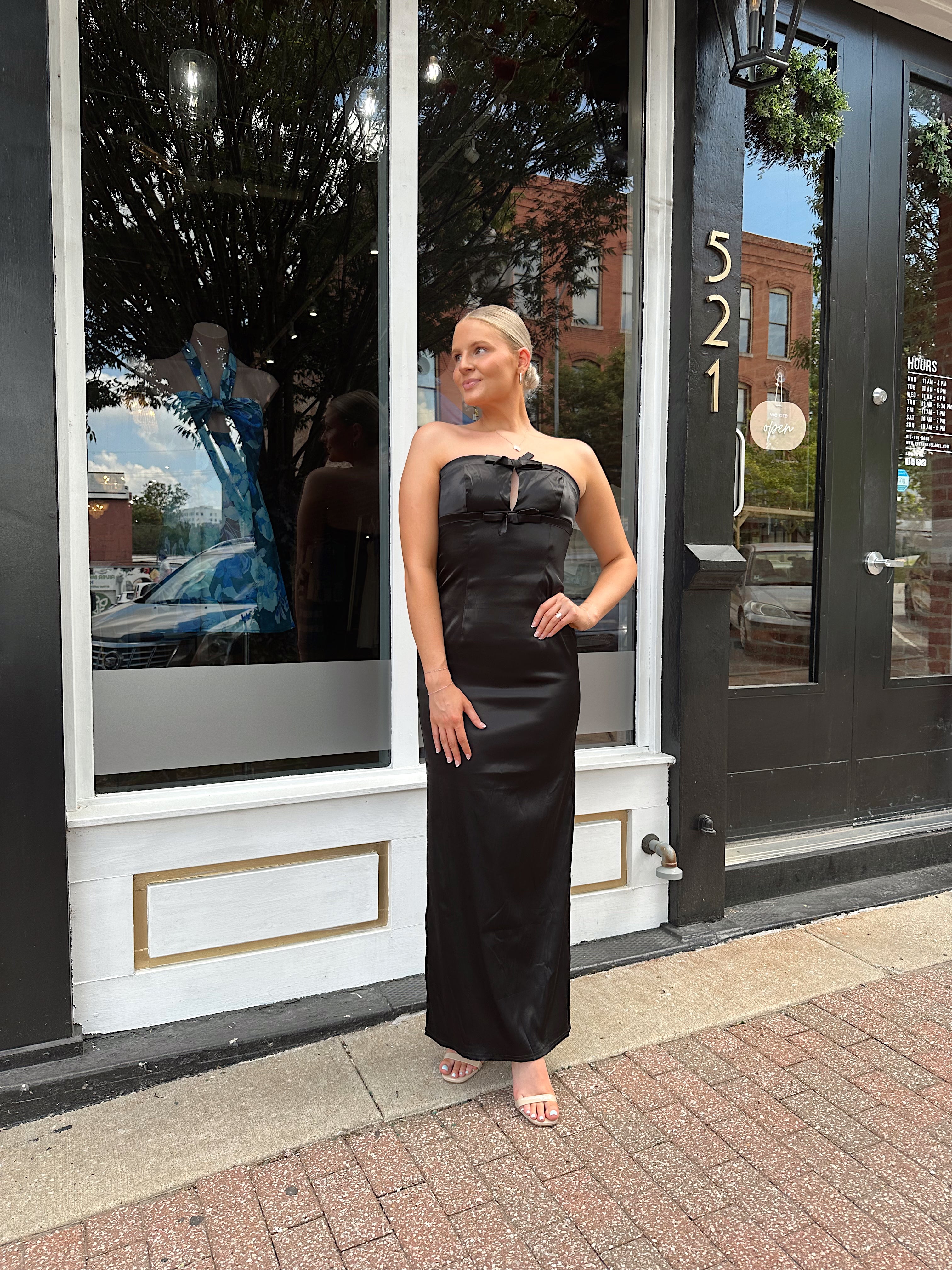 Black satin strapless midi dress with bow detail.
