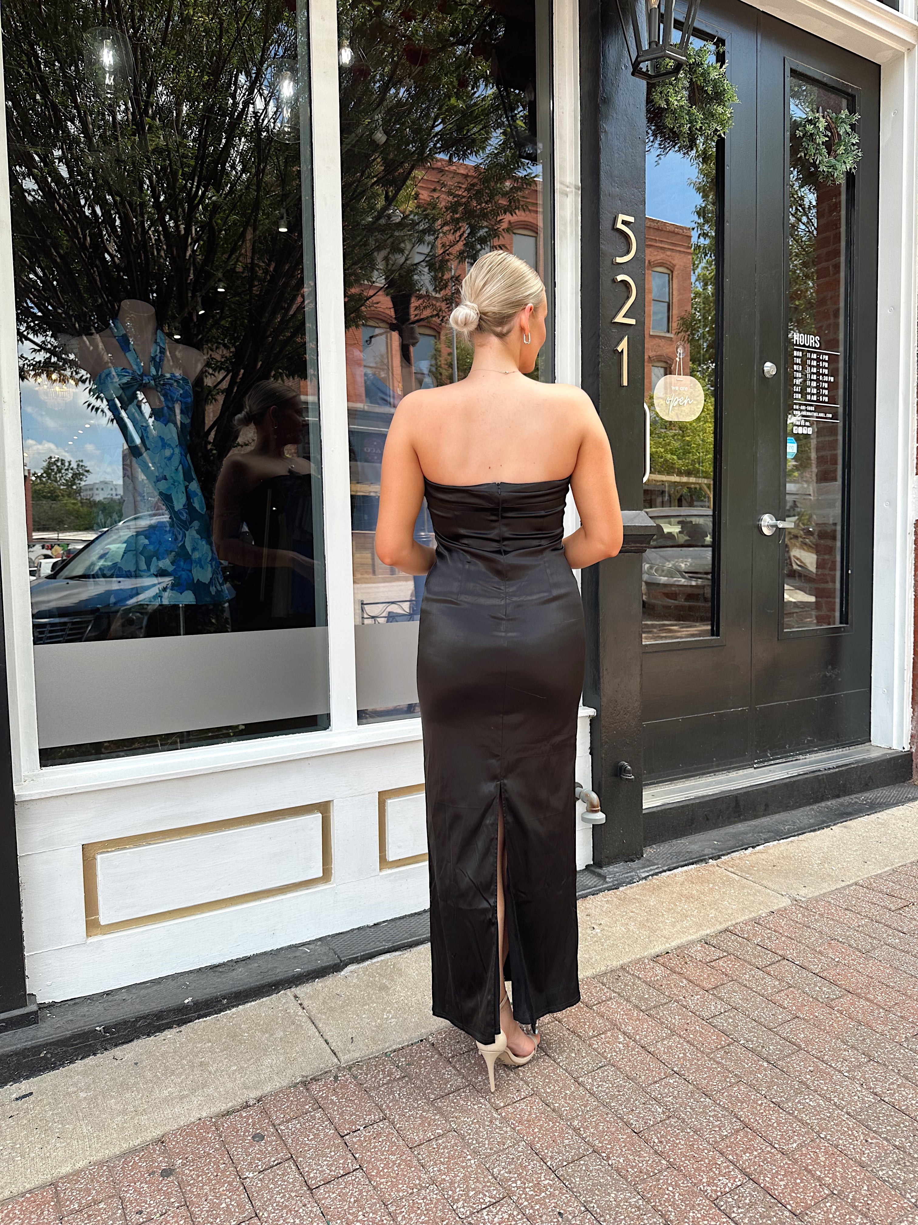 Black satin strapless midi dress with bow detail.