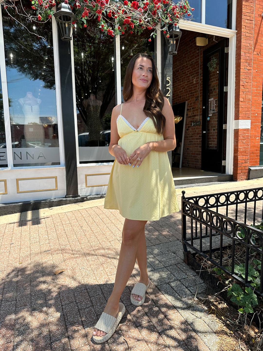 Woman wearing yellow striped mini dress with lace trim neckline, and platform sandals.