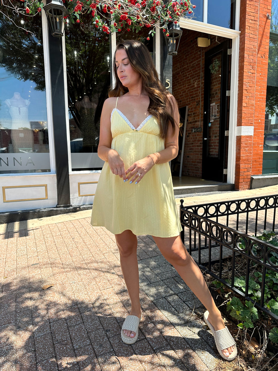 Woman wearing yellow striped mini dress with lace trim neckline, and platform sandals.