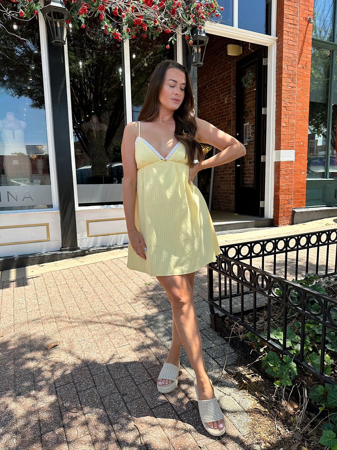 Woman wearing yellow striped mini dress with lace trim neckline, and platform sandals.