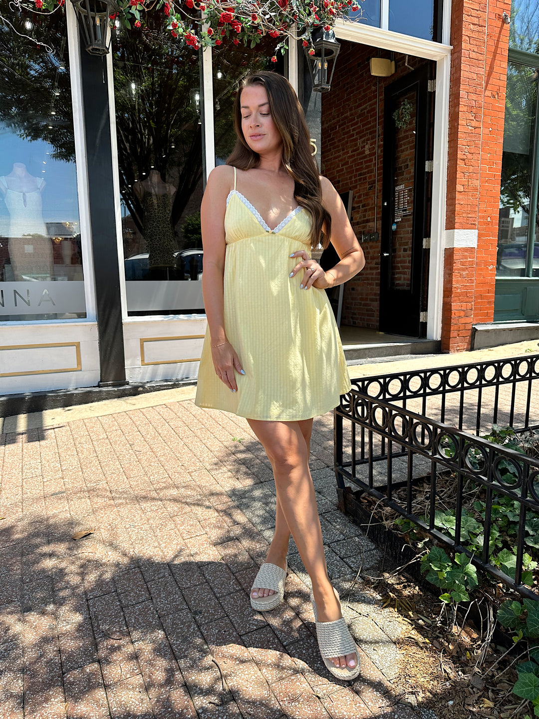 Woman wearing yellow striped mini dress with lace trim neckline, and platform sandals.