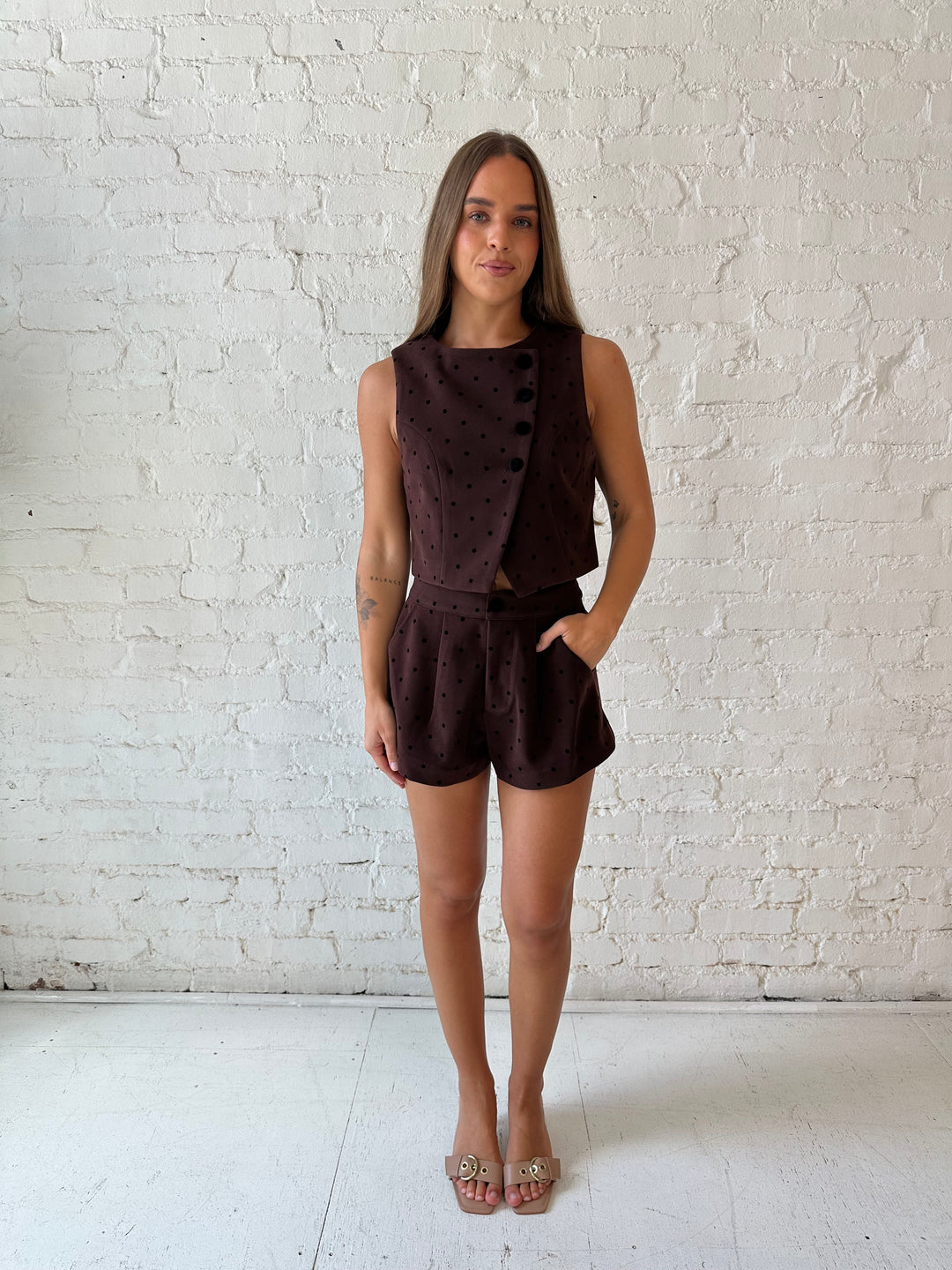Woman wearing brown and black polka dot two piece suede short set. 