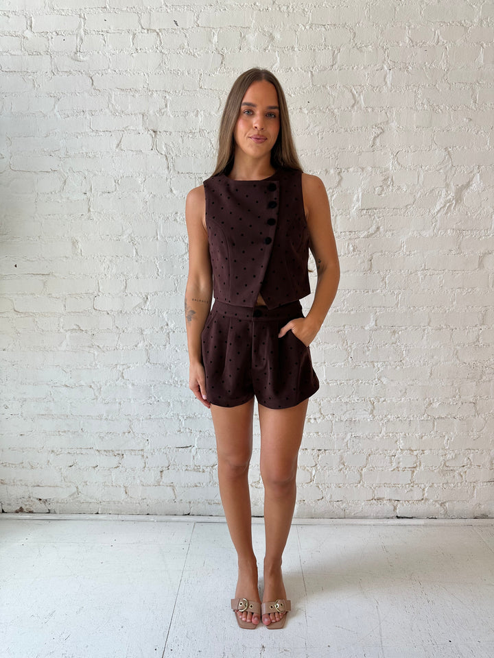 Woman wearing brown and black polka dot two piece suede short set. 