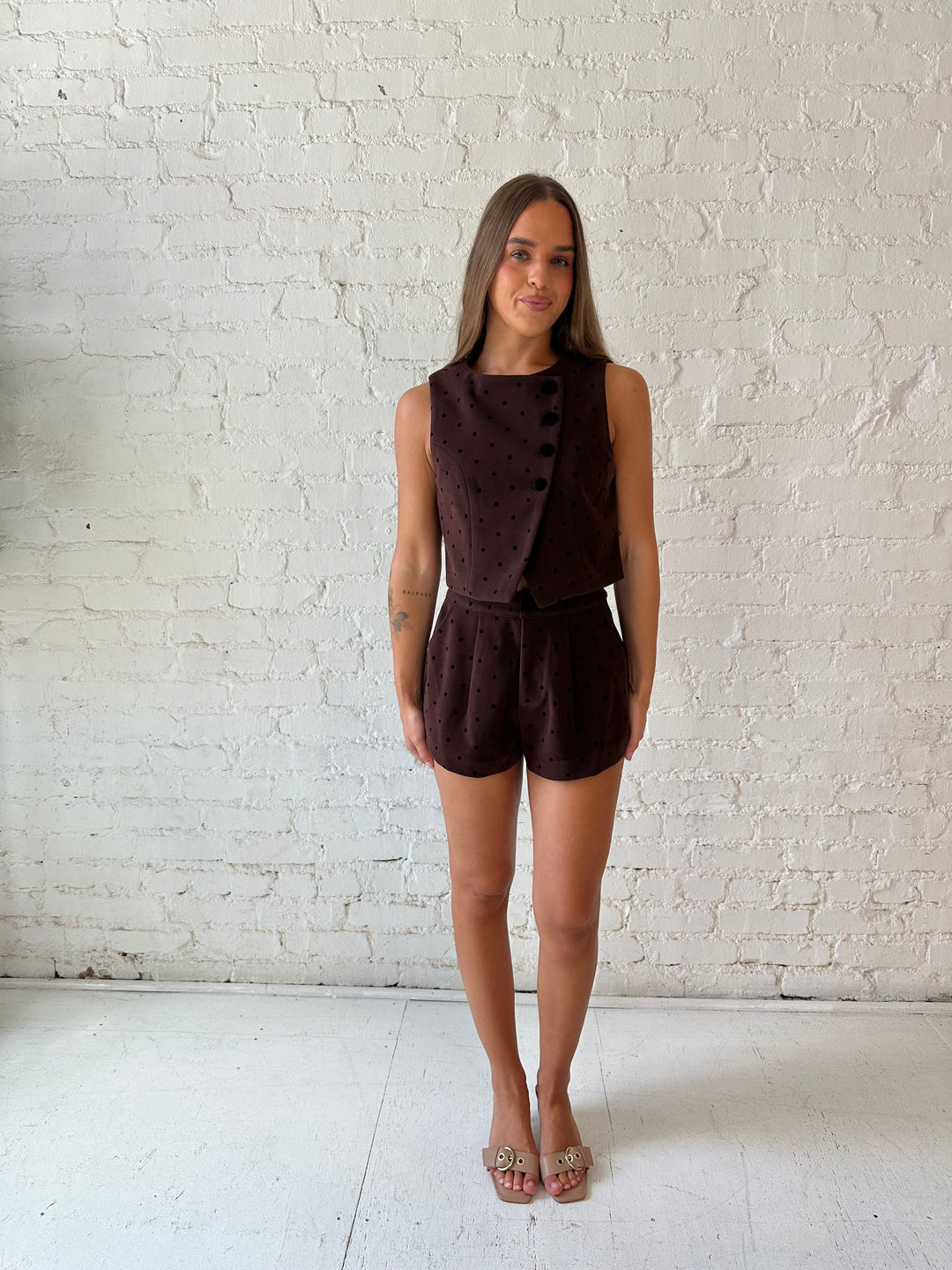 Woman wearing brown and black polka dot two piece suede short set. 