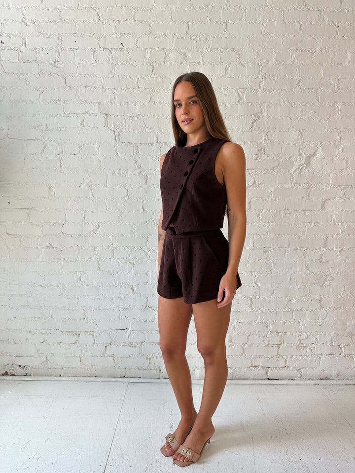 Woman wearing brown and black polka dot two piece suede short set. 