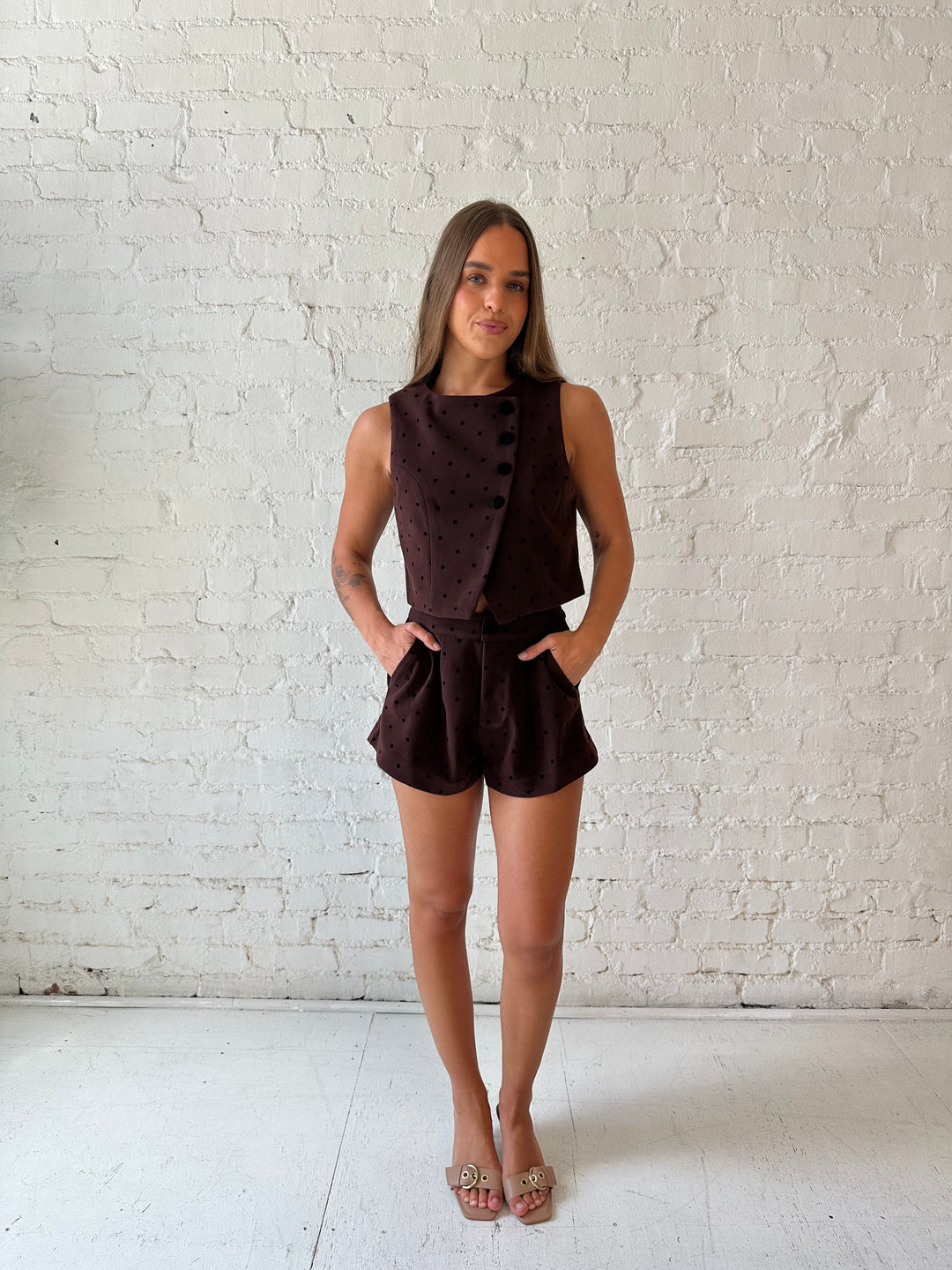 Woman wearing brown and black polka dot two piece suede short set. 