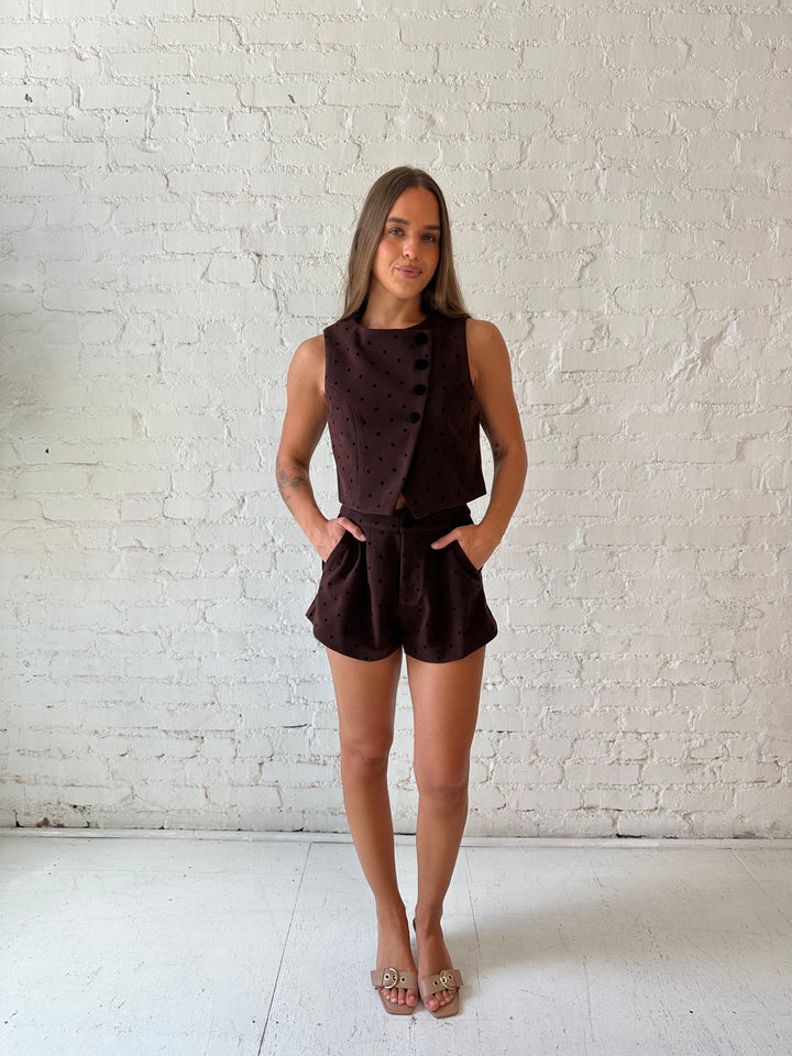 Woman wearing brown and black polka dot two piece suede short set. 