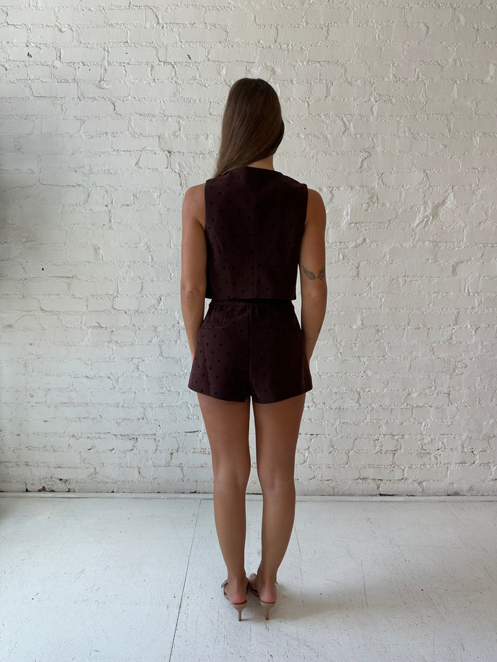 Woman wearing brown and black polka dot two piece suede short set. 