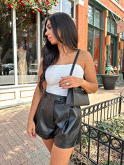 Woman wearing ivory ruched strapless tube top with slight shimmer.