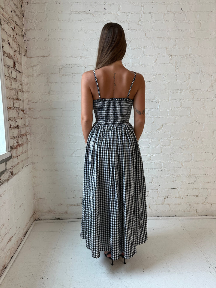 Woman wearing black gingham midi dress with smocked bodice.