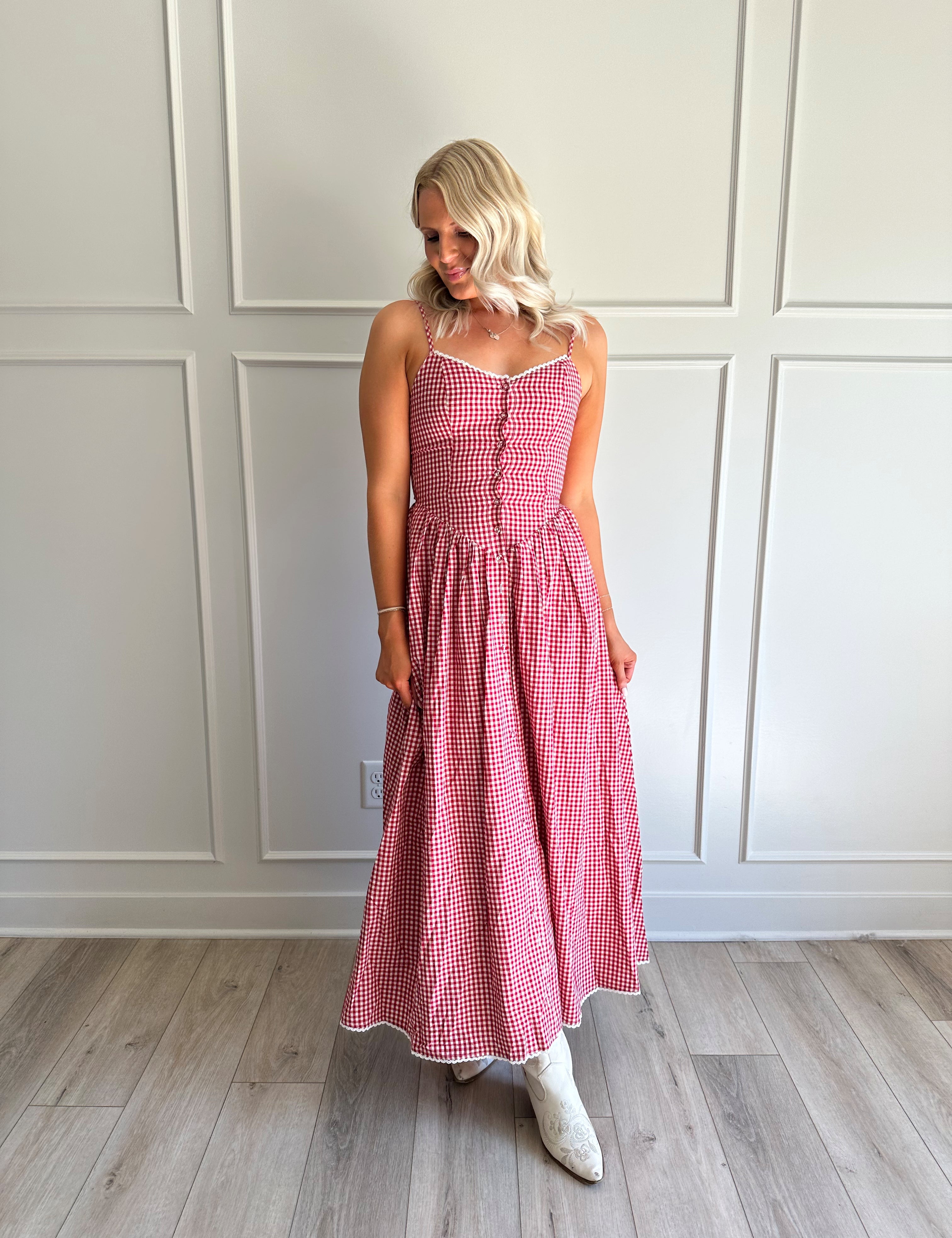 Woman wearing red gingham maxi dress with button detailing. 