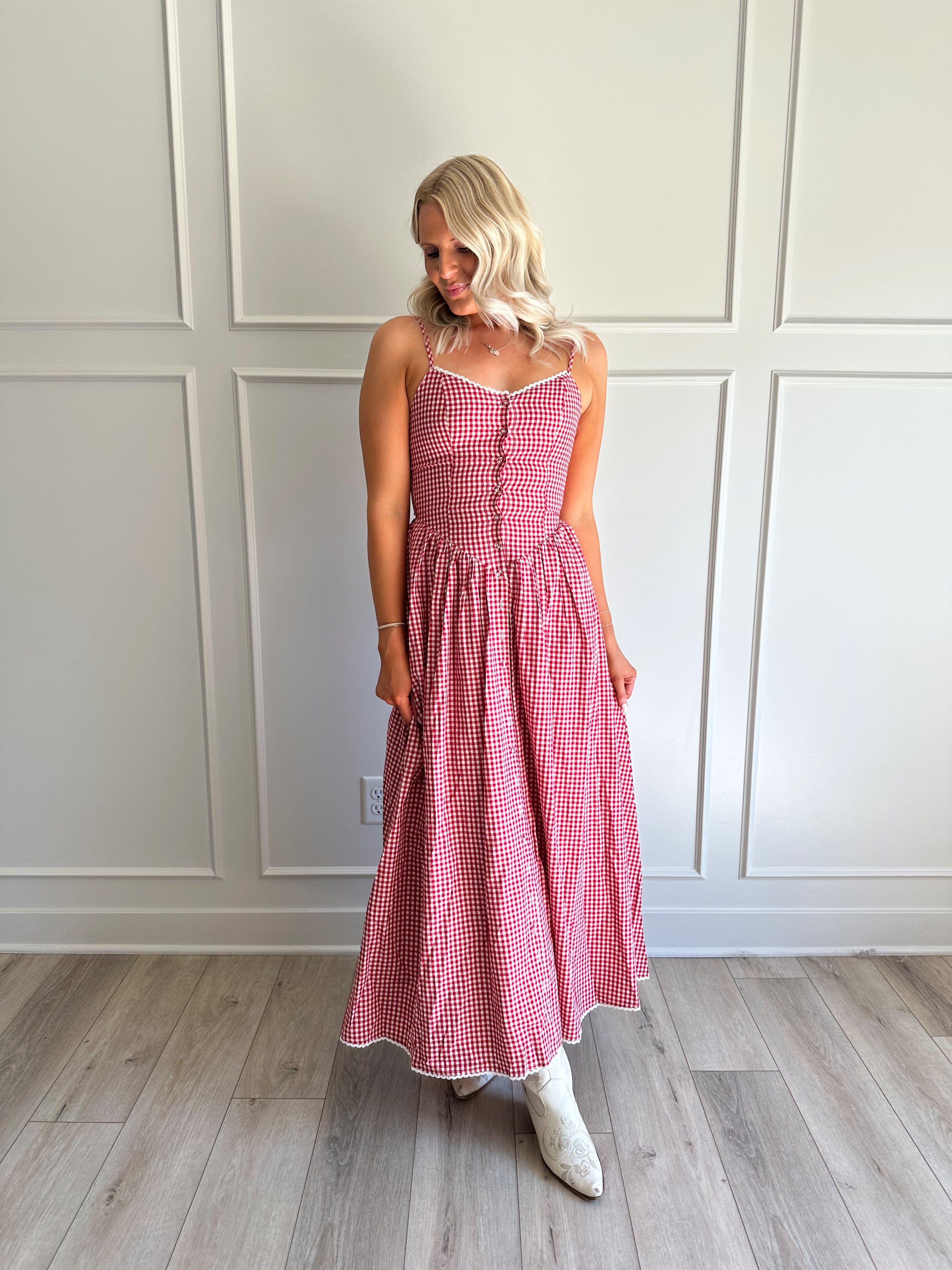 Woman wearing red gingham maxi dress with button detailing. 