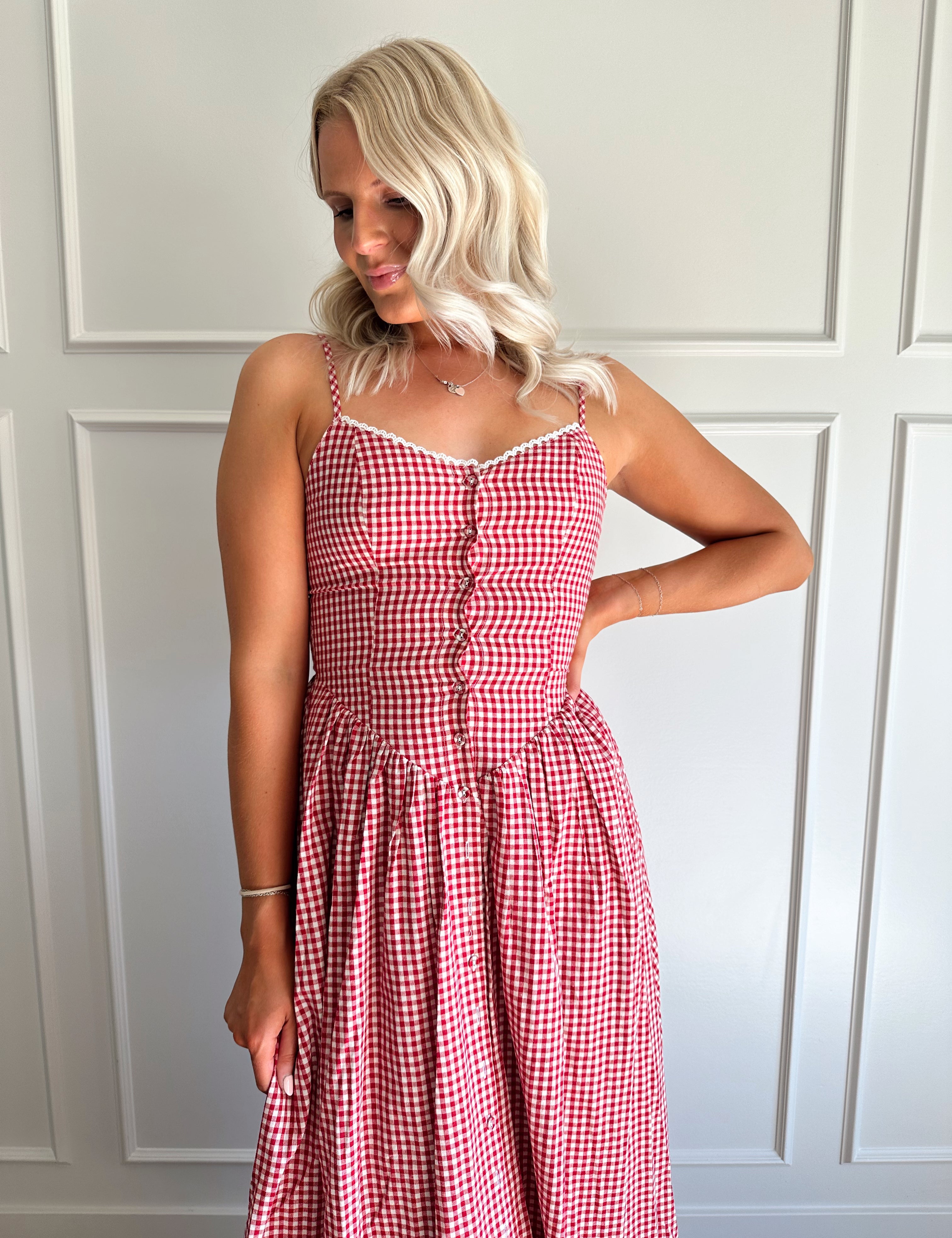 Woman wearing red gingham maxi dress with button detailing. 