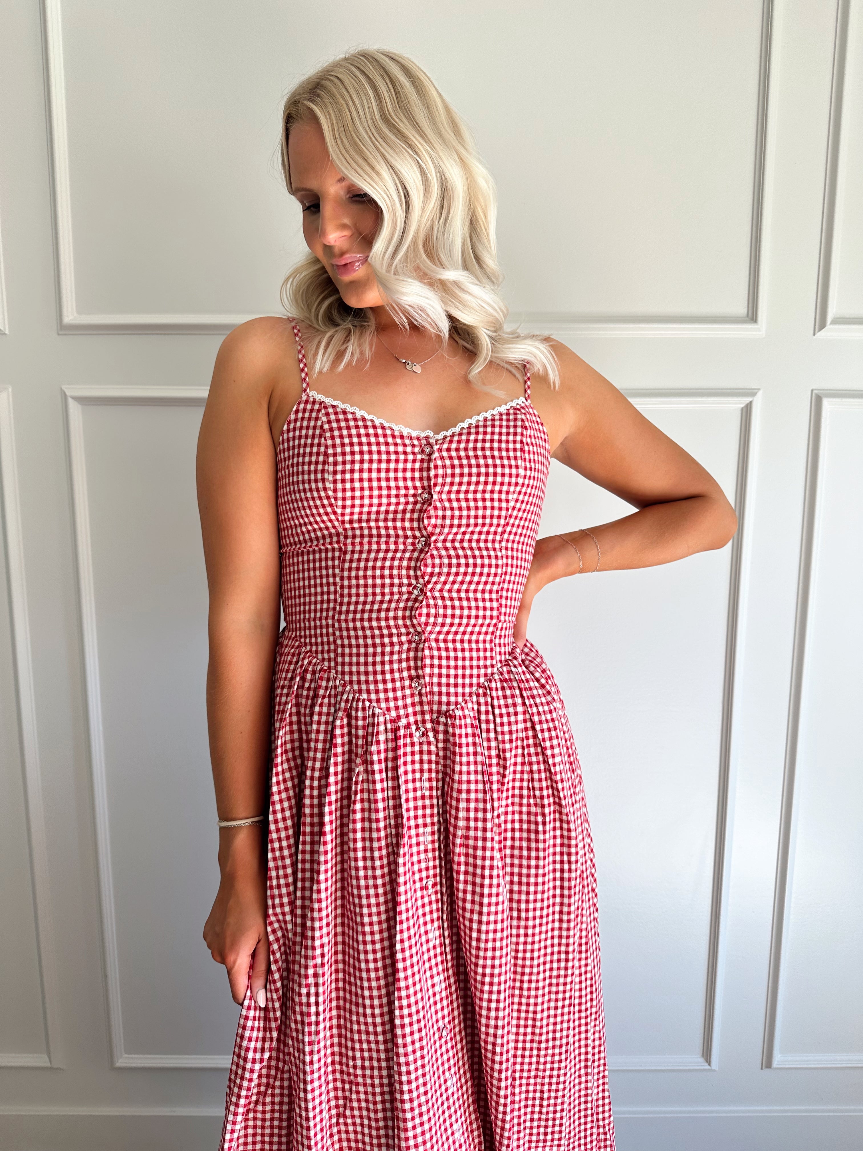 Woman wearing red gingham maxi dress with button detailing. 