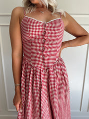 Woman wearing red gingham maxi dress with button detailing. 