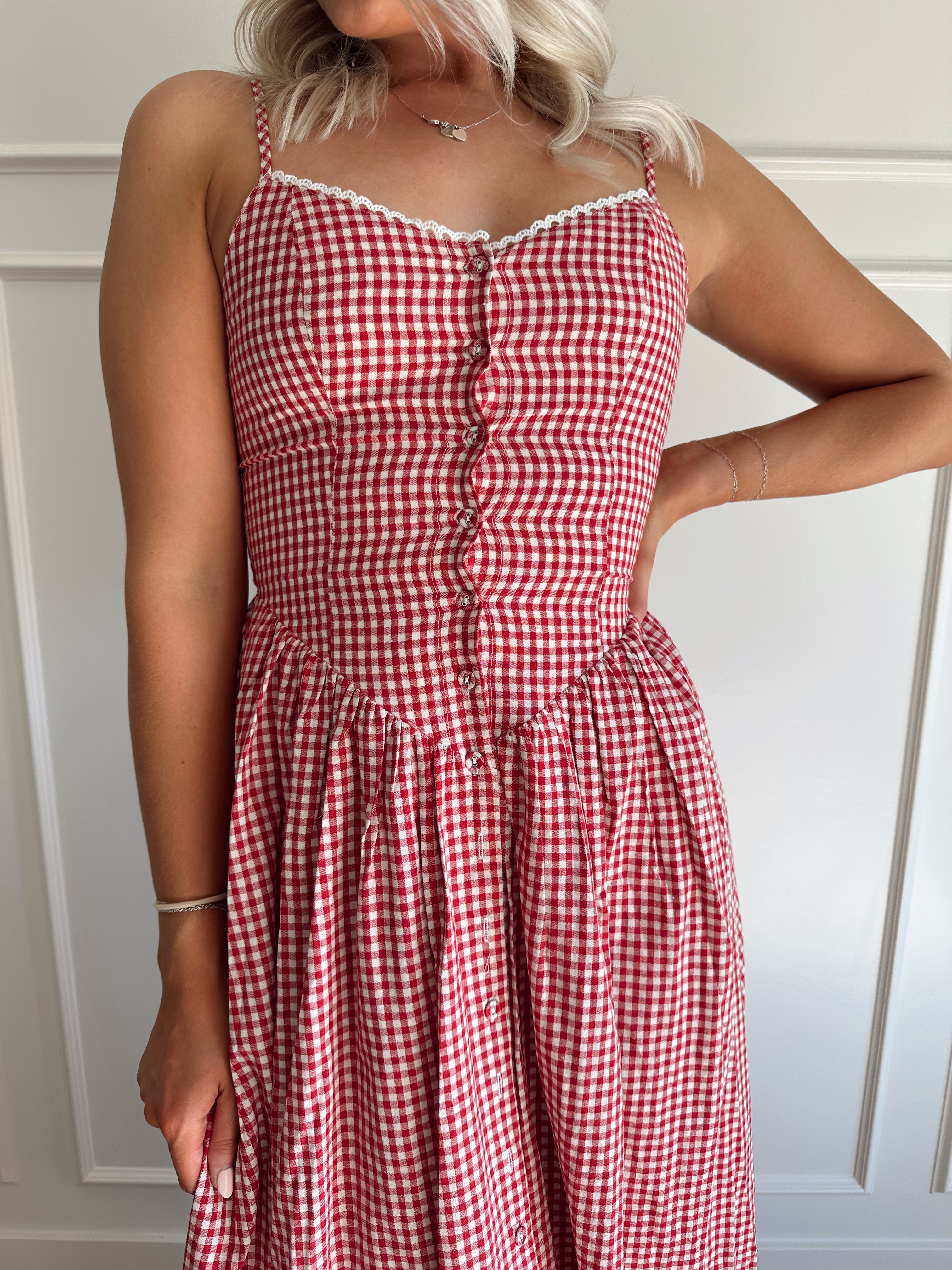 Woman wearing red gingham maxi dress with button detailing. 