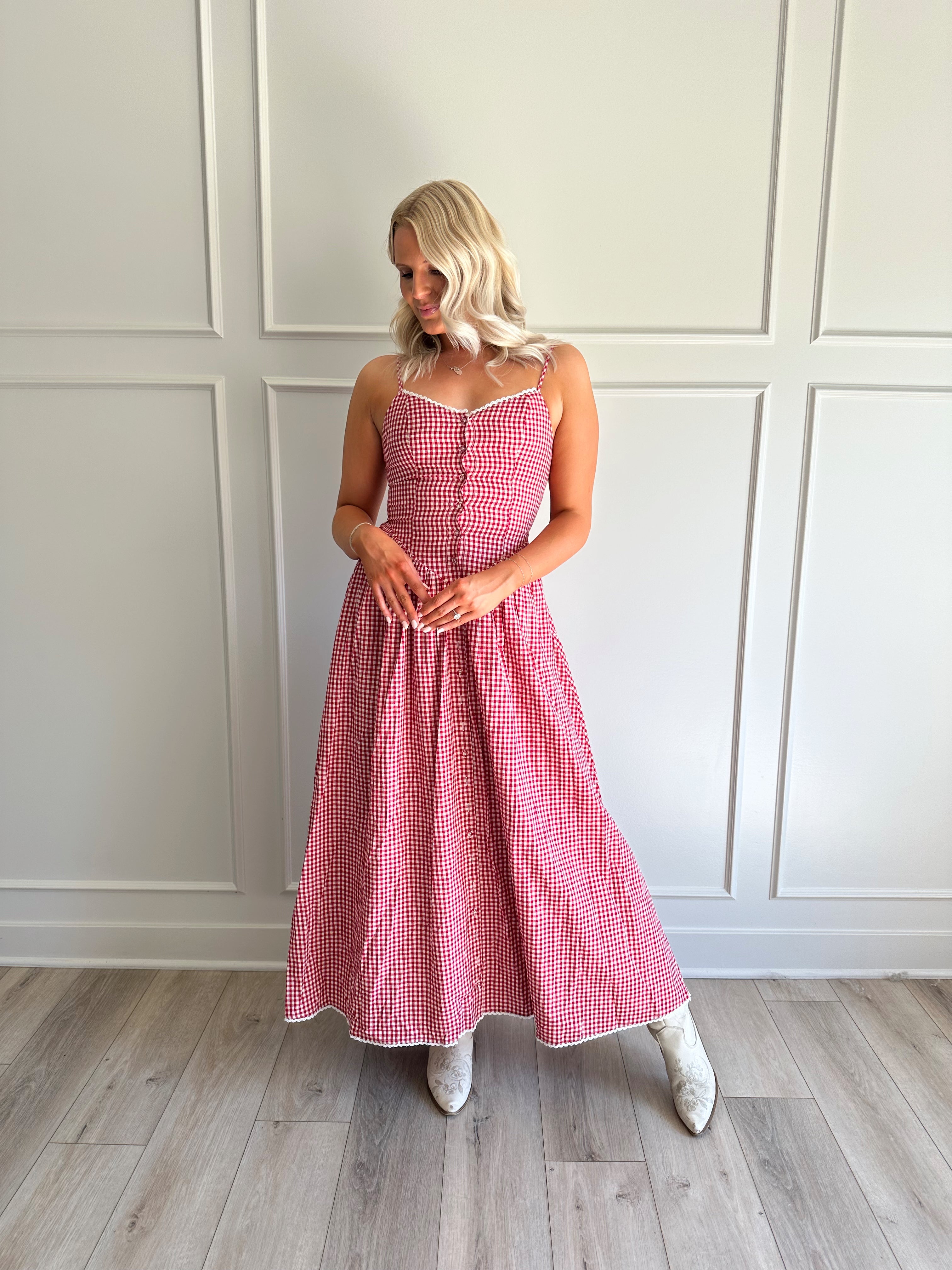Woman wearing red gingham maxi dress with button detailing. 