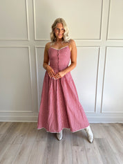 Woman wearing red gingham maxi dress with button detailing. 