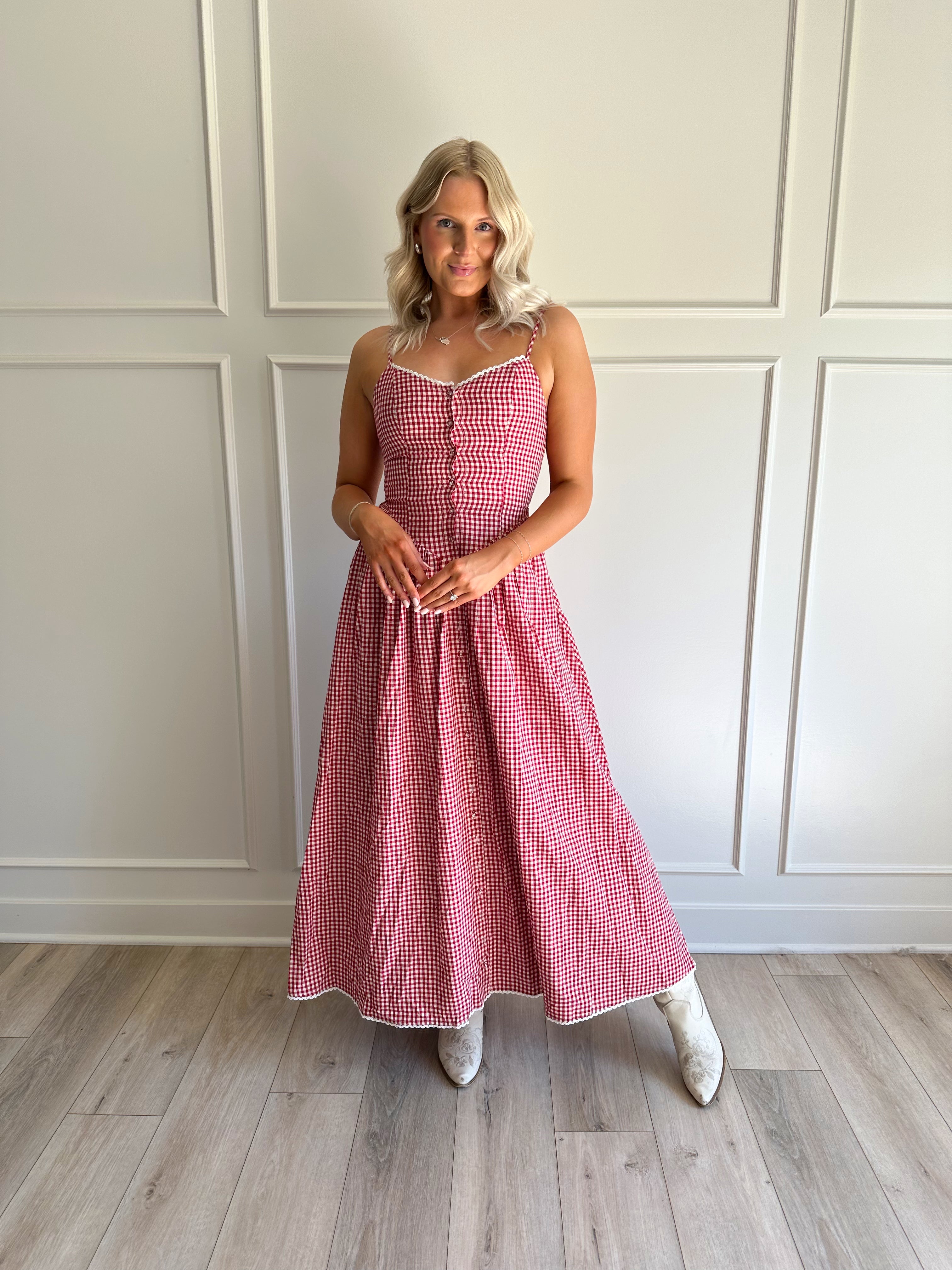 Woman wearing red gingham maxi dress with button detailing. 