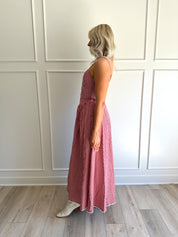 Woman wearing red gingham maxi dress with button detailing. 