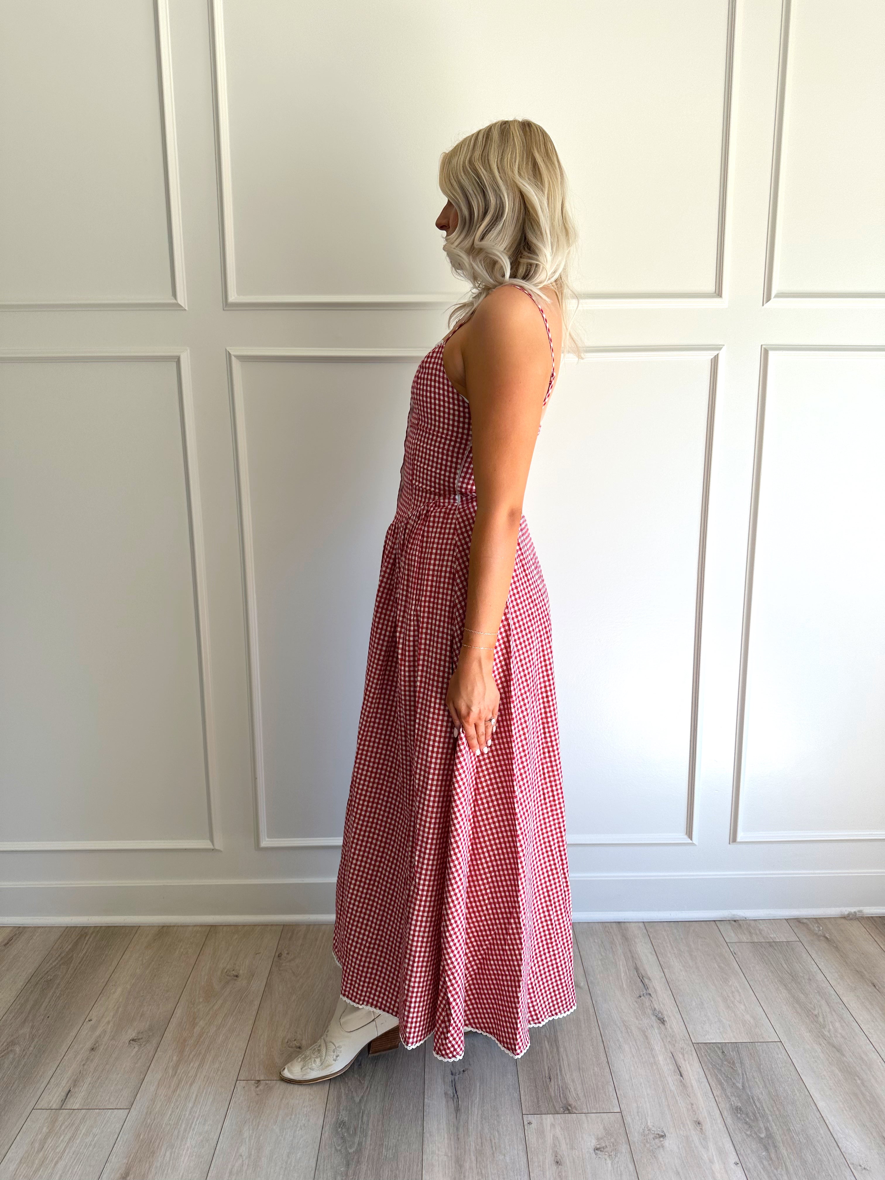Woman wearing red gingham maxi dress with button detailing. 